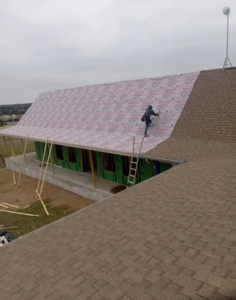 Worker preparing underlayment for a metal roof installation in Lindenhurst